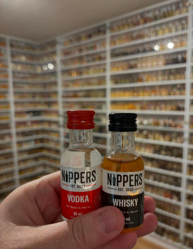 Rotem Ben holding his Nippers mini bottles in-front of his 10,000+ mini bottle collection